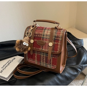 Detailansicht der Retro-Tasche aus Karo-Wolle und braunem Leder mit Plüsch-Anhänger