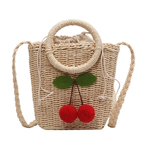 Handmade woven straw crossbody bag with red cherry accents and drawstring lining