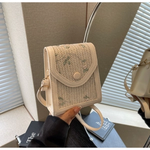 Détail d'un petit sac bandoulière en paille beige avec broderie florale et finition cuir