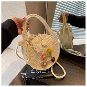Detail der runden Strohtasche mit 3D-Blumen und weißer Spitzenschleife