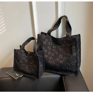 Detail of black tote bags in two sizes featuring 3D floral embossed fabric texture