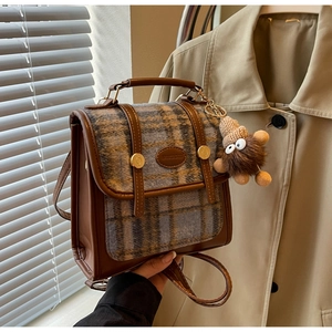 Detail der Retro-Karo-Tasche mit braunem Lederbesatz und süßem Plüschbären-Anhänger