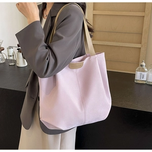 Close-up of a large purple tote bag with fashion patch and wide shoulder strap