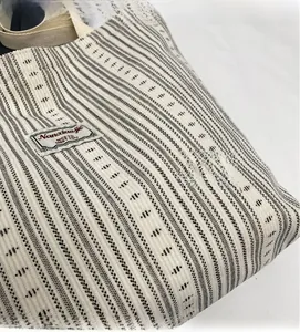 Close-up of white corduroy tote bag featuring black stripes and brand woven label