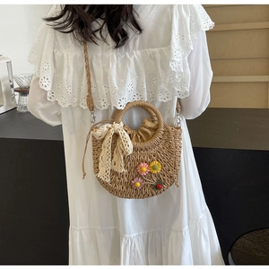 Detail of hand-woven straw bag with colorful floral decor and lace bow in studio