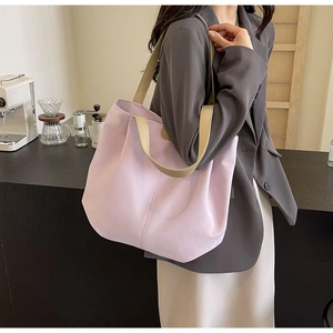 Detail of light purple tote bag with khaki straps worn by a model in a minimalist cafe