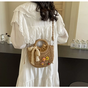 Detail of handmade woven straw bag featuring floral crochet accents and lace bow detail