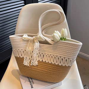Grand sac de plage bicolore en paille tressée avec nœud en dentelle sur chaise blanche