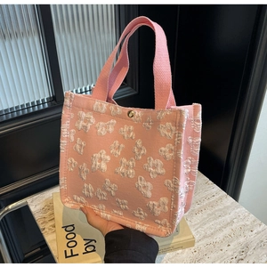 Detail of pink canvas tote bag featuring 3D floral relief pattern and metal snap closure