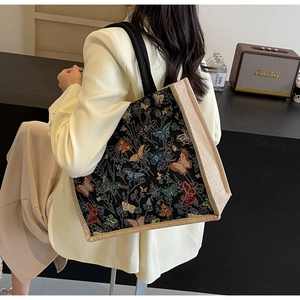 Détail de broderie papillon colorée sur cabas en jacquard noir avec bordure en toile