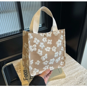 Detail of khaki canvas tote with 3D floral texture, woven handle and side snap button