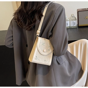 Détail d'un sac bandoulière blanc tressé avec broderie florale et rabat magnétique