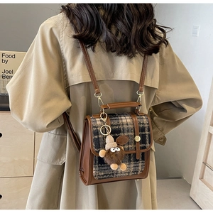 Detail des Tweed-Karo-Rucksacks mit Vintage-Schnalle und flauschigem Monster-Anhänger
