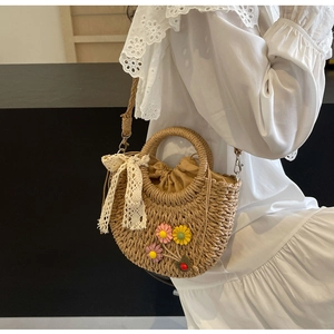 Detail of hand-woven straw bag with lace bow and floral accents on a white dress