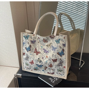 Détail du sac cabas en toile beige avec imprimés papillons sous les ombres des stores