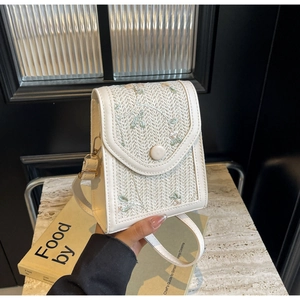 Gros plan détaillé d'un sac bandoulière blanc tissé avec de délicates broderies florales