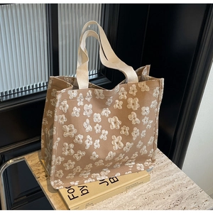Close-up of large khaki canvas tote bag with 3D floral texture on stone tabletop