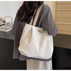 Detail of off-white tote bag with brown handles and FASHION embossed leather patch