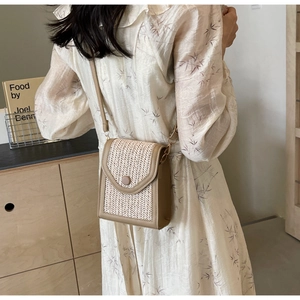 Detail of hand-woven crossbody phone bag featuring cream straw texture and leather trim