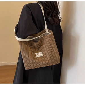 Detail of dark brown corduroy tote bag featuring white fabric strap and logo label