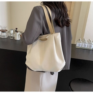 Detail of cream tote bag with khaki straps shown in a minimalist cafe setting