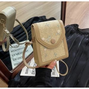 Détail du sac de téléphone en paille avec broderie florale et finitions en cuir