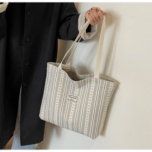Detail of striped corduroy tote bag featuring minimalist label and sturdy handles