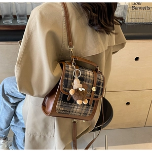 Detail eines Vintage-Rucksacks mit Karomuster, Leder-Schnalle und Plüsch-Anhänger