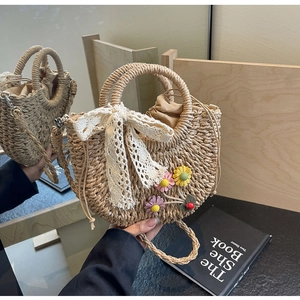 Detail of handwoven straw bag featuring delicate floral embroidery and white lace bow