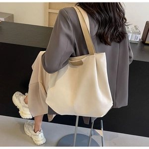 Detail of cream white tote bag with visible vertical stitching and fashion tag detail