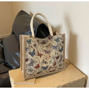 Détail du grand sac cabas tissé avec motifs papillons sur un socle en pierre