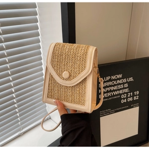 Detail of hand-woven straw crossbody bag with white leather trim and gold hardware clasp