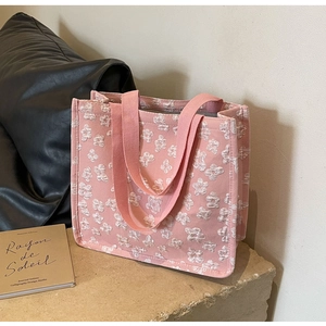 Detail of pink canvas tote bag featuring 3D floral textures and matching woven handles