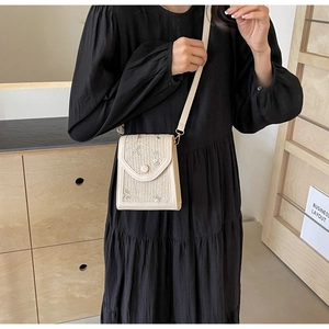 Détail d'un sac bandoulière en paille crème avec broderies florales vertes et brunes