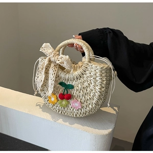 Close-up of handmade straw bucket bag with floral embroidery and lace bow detail