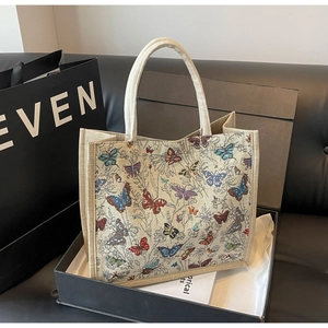 Vue détaillée d'un grand sac cabas crème avec imprimés papillons colorés dans un coffret