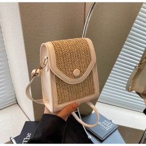 Detail of handmade woven straw and white leather crossbody bag with golden buckle