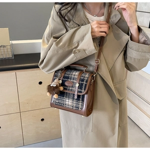 Detail der Vintage-Umhängetasche aus braunem Leder und Karostoff mit Plüschbären-Anhänger