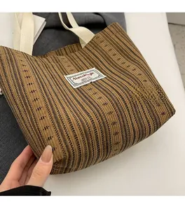 Detailed texture of brown striped knitted tote bag with white woven handles and fabric label