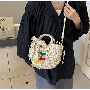 Detail of straw woven bag with knitted cherry and floral decor plus lace bow accent