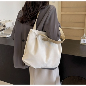 Fashionable beige tote bag with woven straps shown in a stylish cafe setting