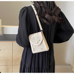 Détail du petit sac bandoulière en paille crème avec broderie florale verte et rabat