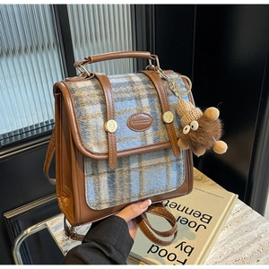 Detail eines Vintage-Rucksacks aus kariertem Stoff mit braunem Lederbesatz und Schnalle