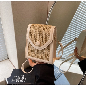 Detail of beige straw woven crossbody bag with cream leather trim and button closure