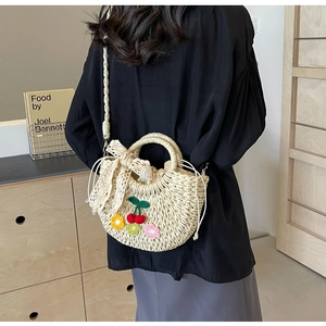 Detail of straw woven bucket bag with lace bow and crochet floral cherry patches