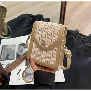 Close-up of handmade woven straw crossbody bag with PU leather and gold magnetic buckle