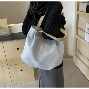 Detail of light blue tote bag with matte leather texture and cream webbing handles