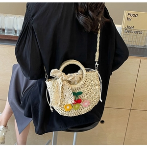 Detail of handmade straw bag with crochet cherry flower decor and lace bow accent