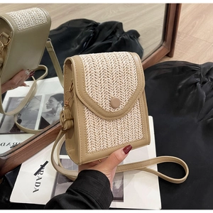 Detail of hand-woven straw crossbody bag with light khaki faux leather trim and gold buckle