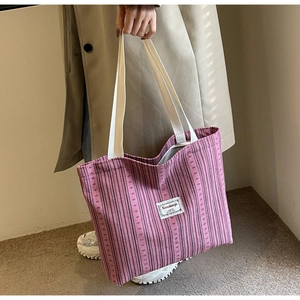 Detailed close-up of large pink corduroy tote bag with black stripes and brand woven label